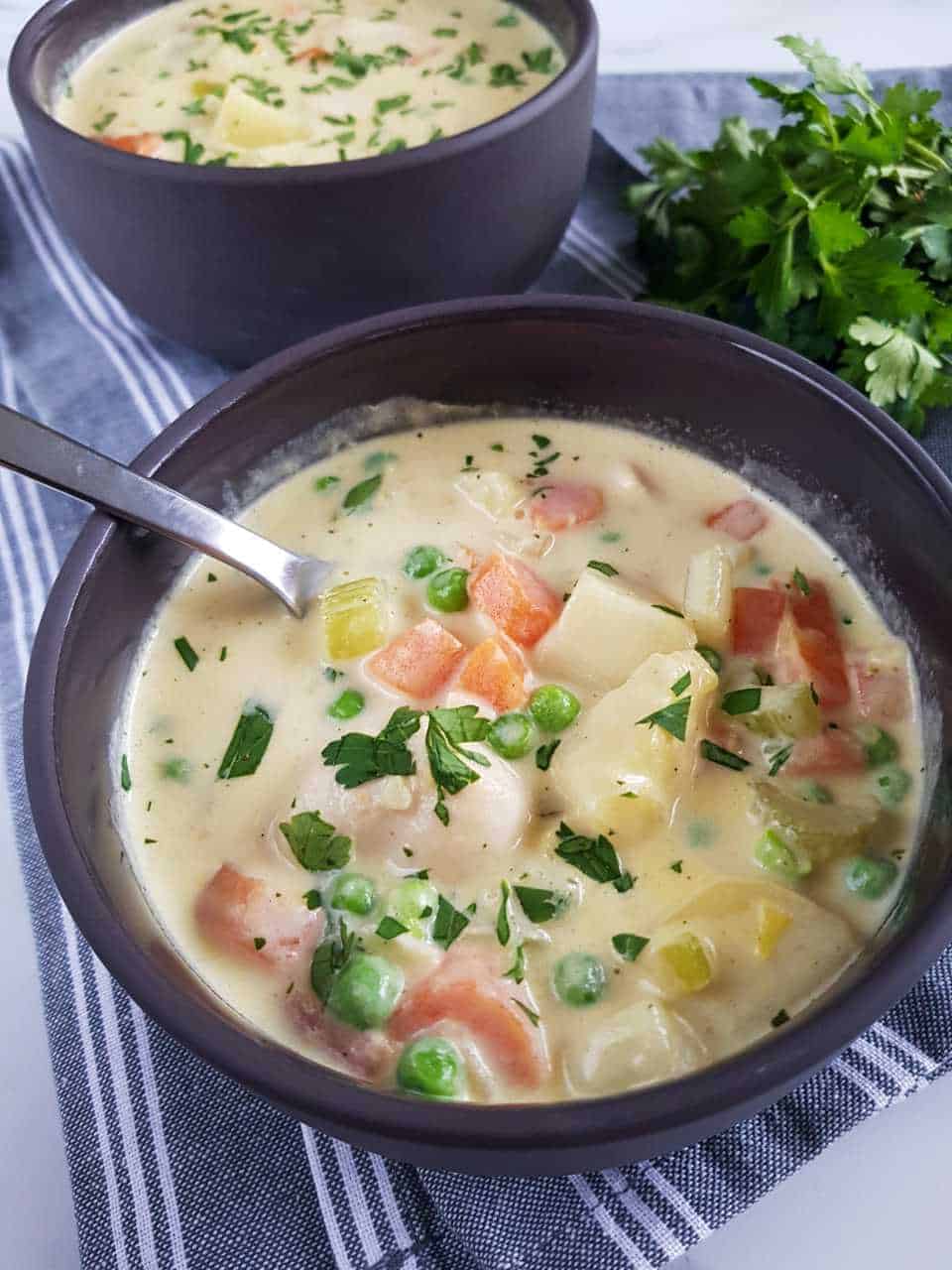 chicken and vegetable soup in gray bowls with spoons.