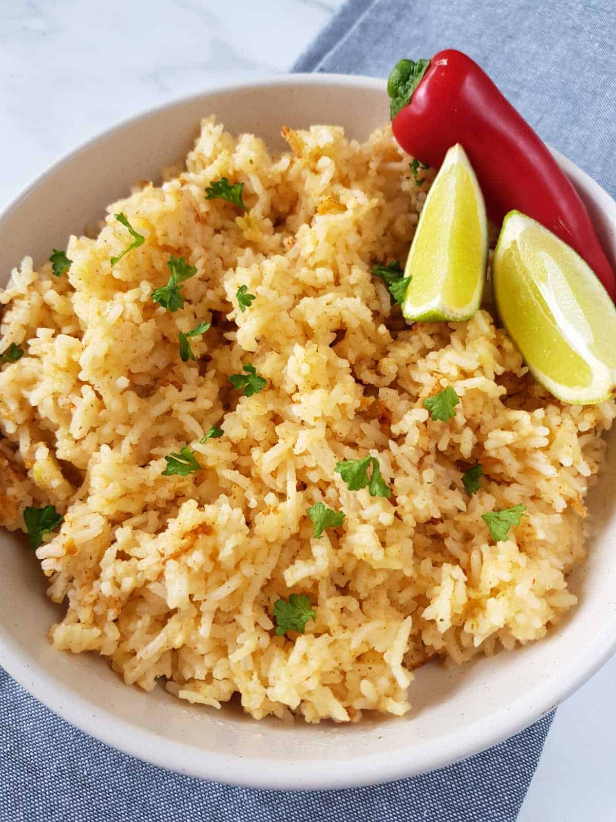 Chili and lime rice in a white bowl on a tablecloth.