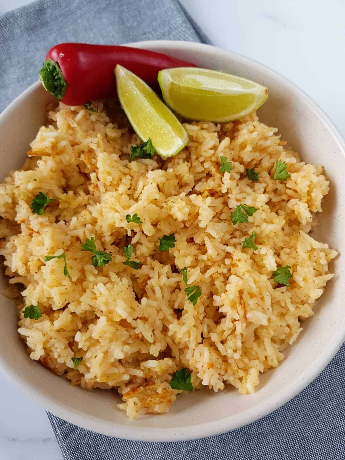 Chili lime rice garnished with herbs, lime wedges and a red chili.