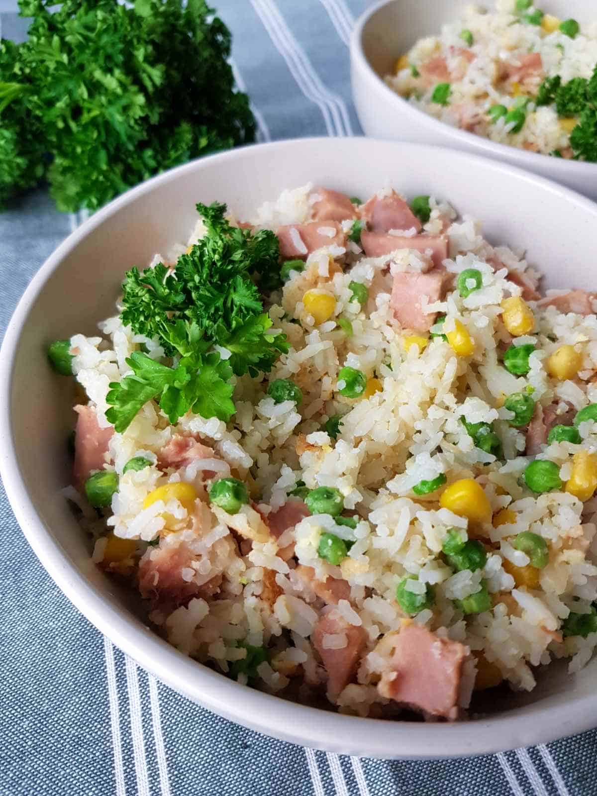 Gammon fried rice in white bowls on a tablecloth.