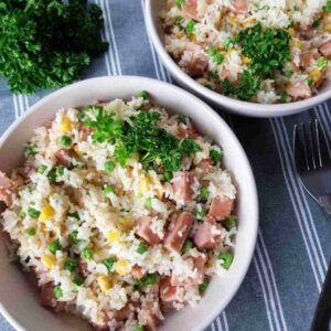 a bowl of fried rice with gammon, peas and corn.