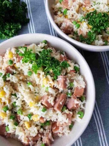 a bowl of fried rice with gammon, peas and corn.