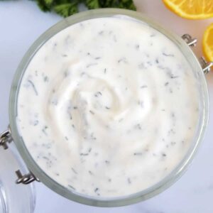 Ranch dressing in a jar with lemon and parsley on the side.