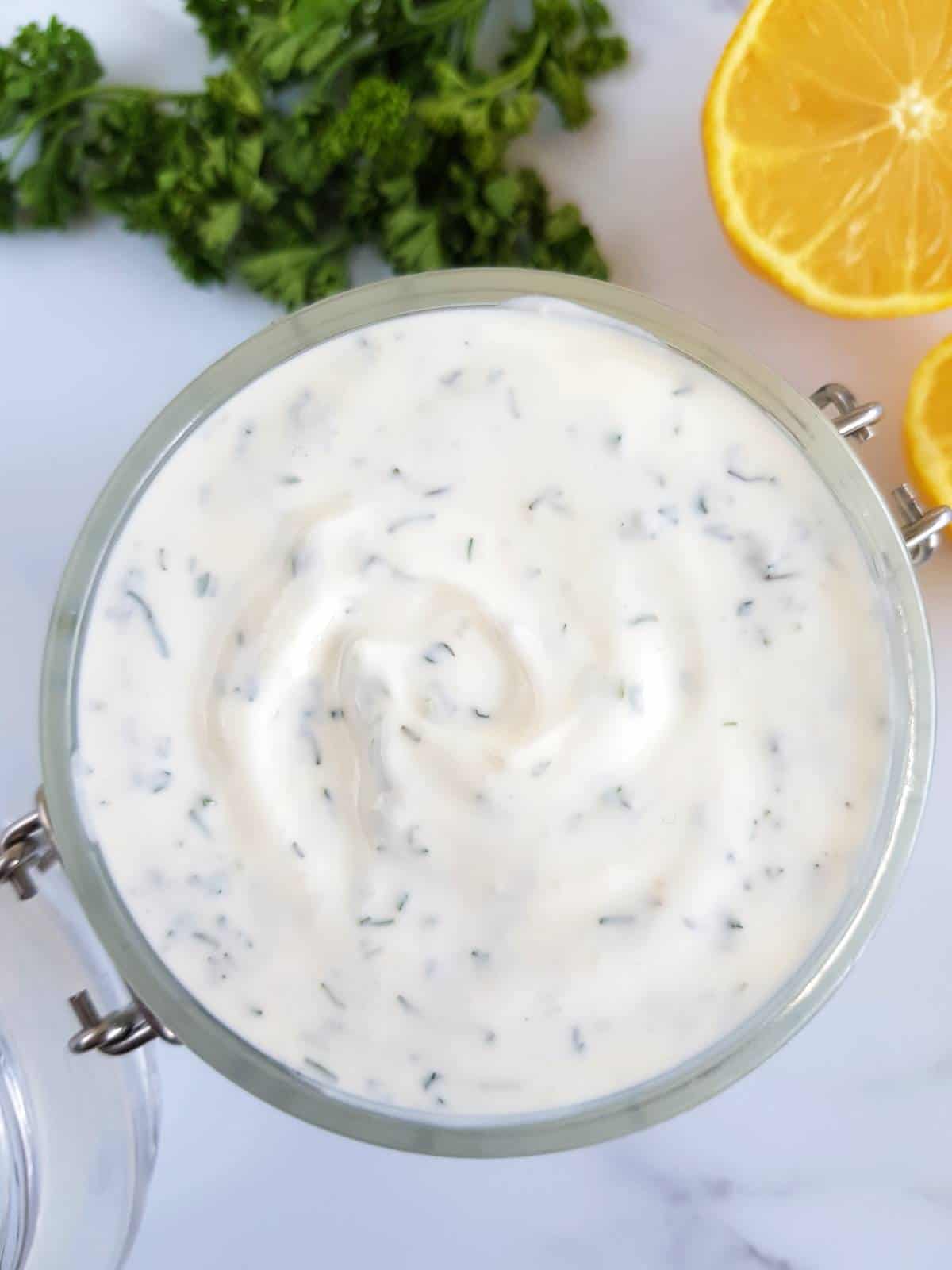 Homemade ranch in a jar with lemon and parsley on the side.