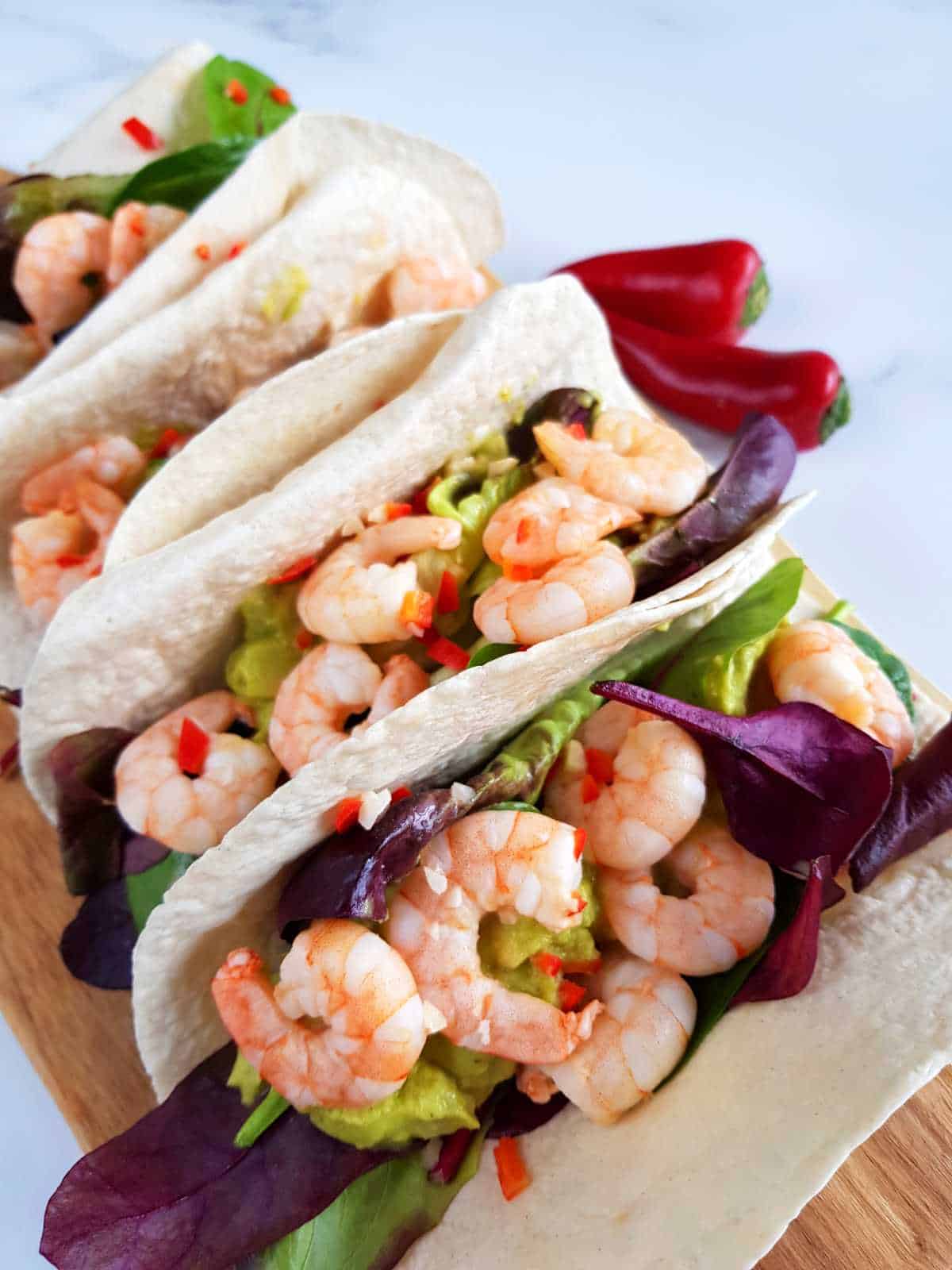 Lime and chili shrimp tacos with fresh chilies on the side.