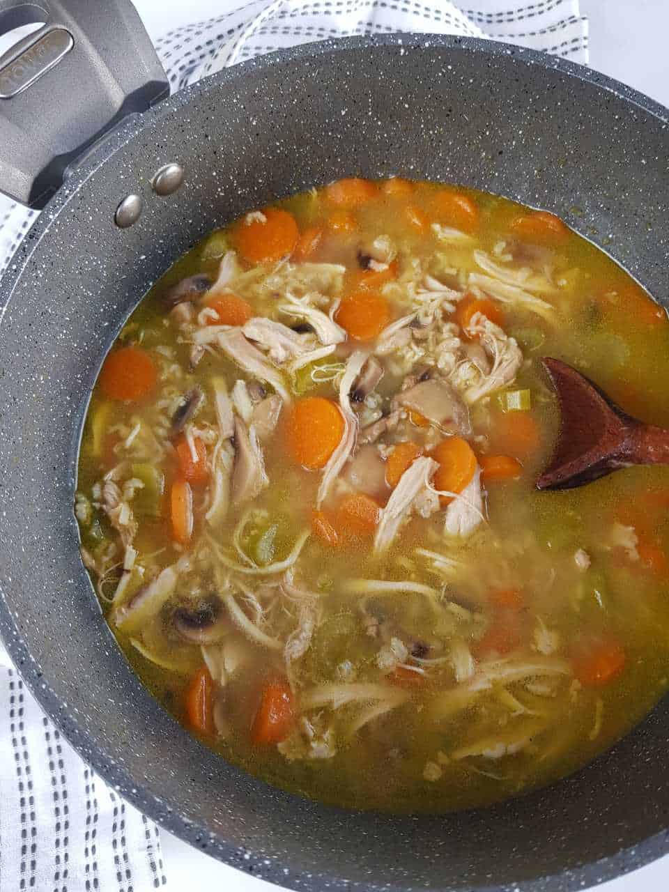 Chicken and rice soup in a large pot on a marble table.