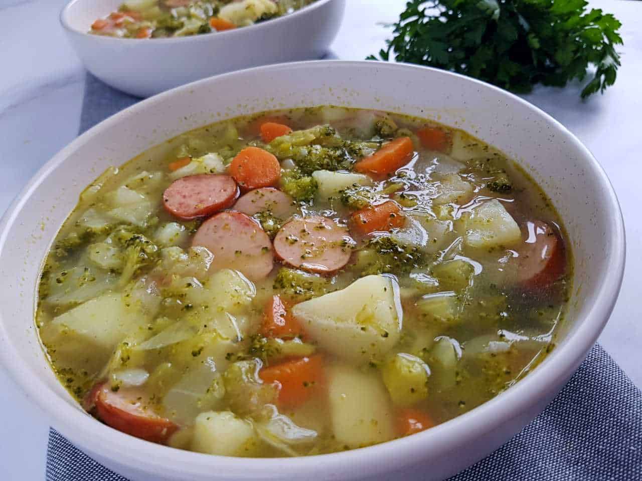 Sausage and vegetable soup in white bowls.