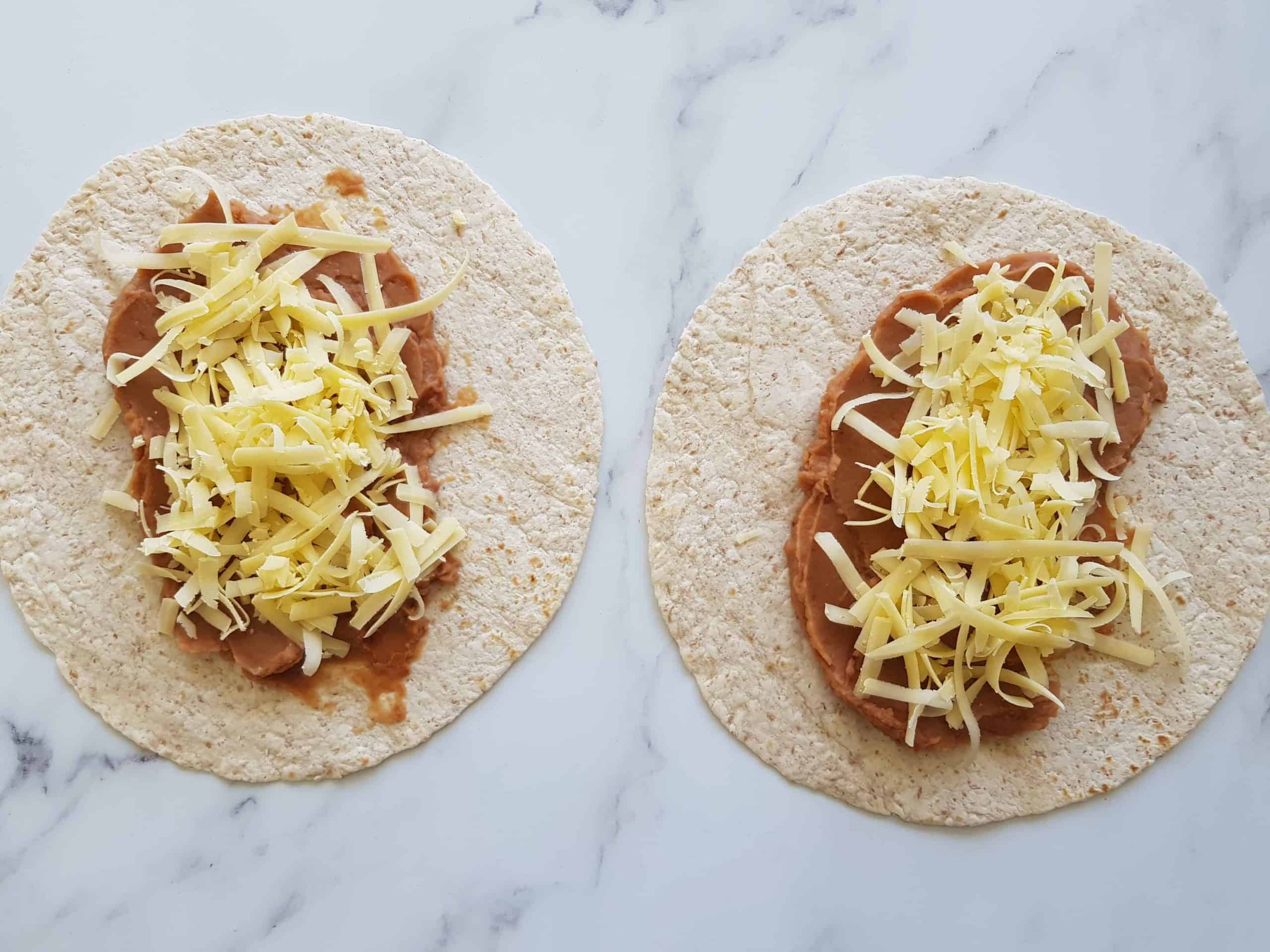 Tortilla wraps with refried beans and grated cheese.