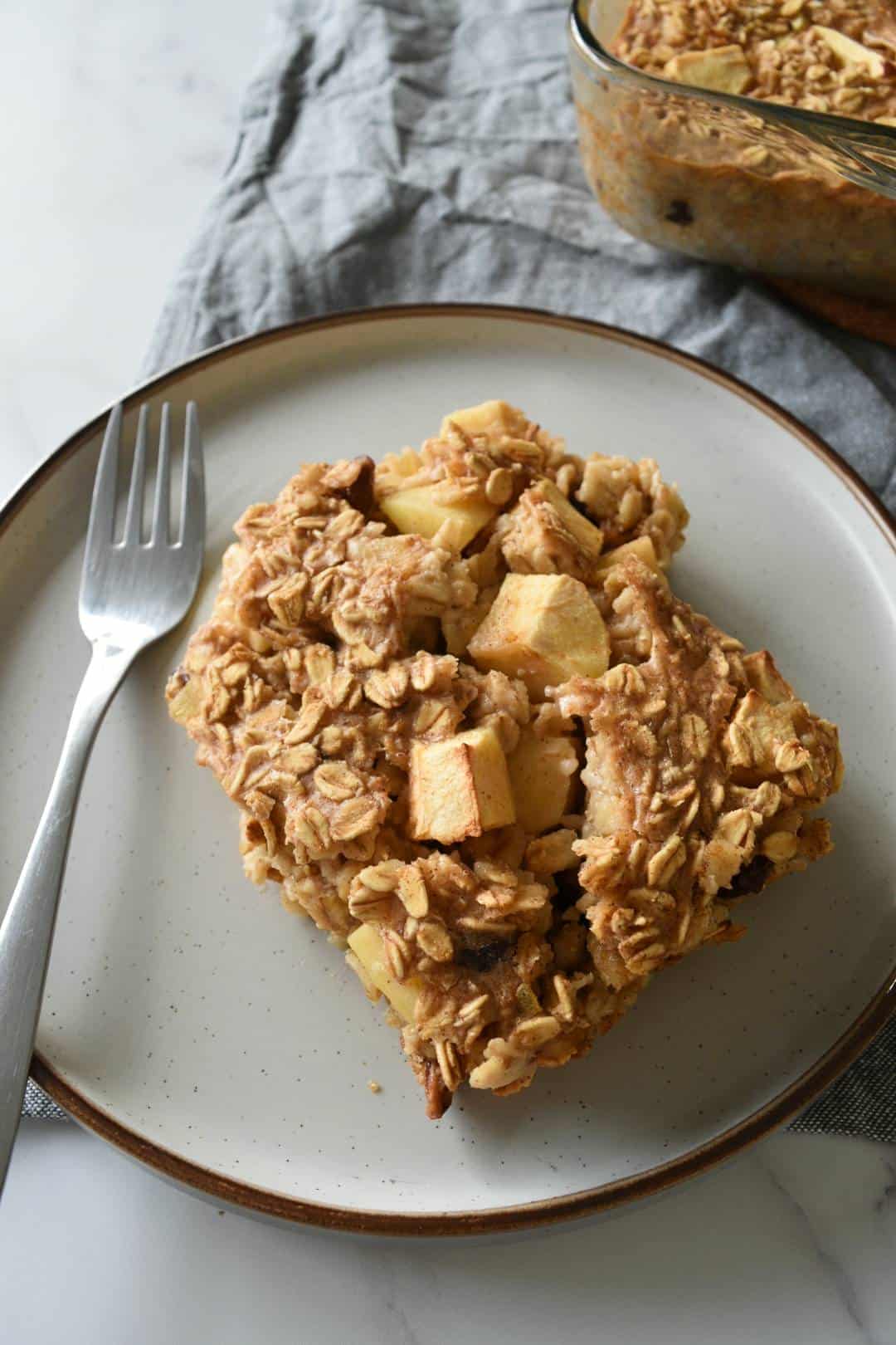 A plate of baked apple cinnamon oats with a fork on the side.