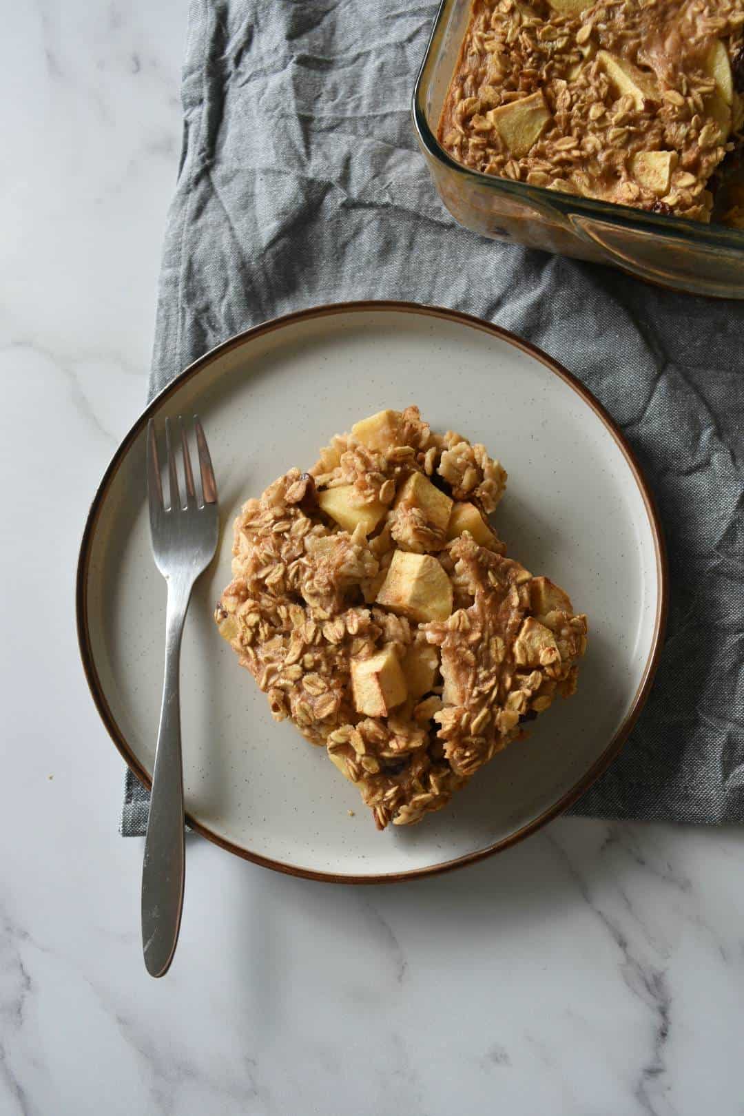 Apple cinnamon baked oats on a plate with a fork.