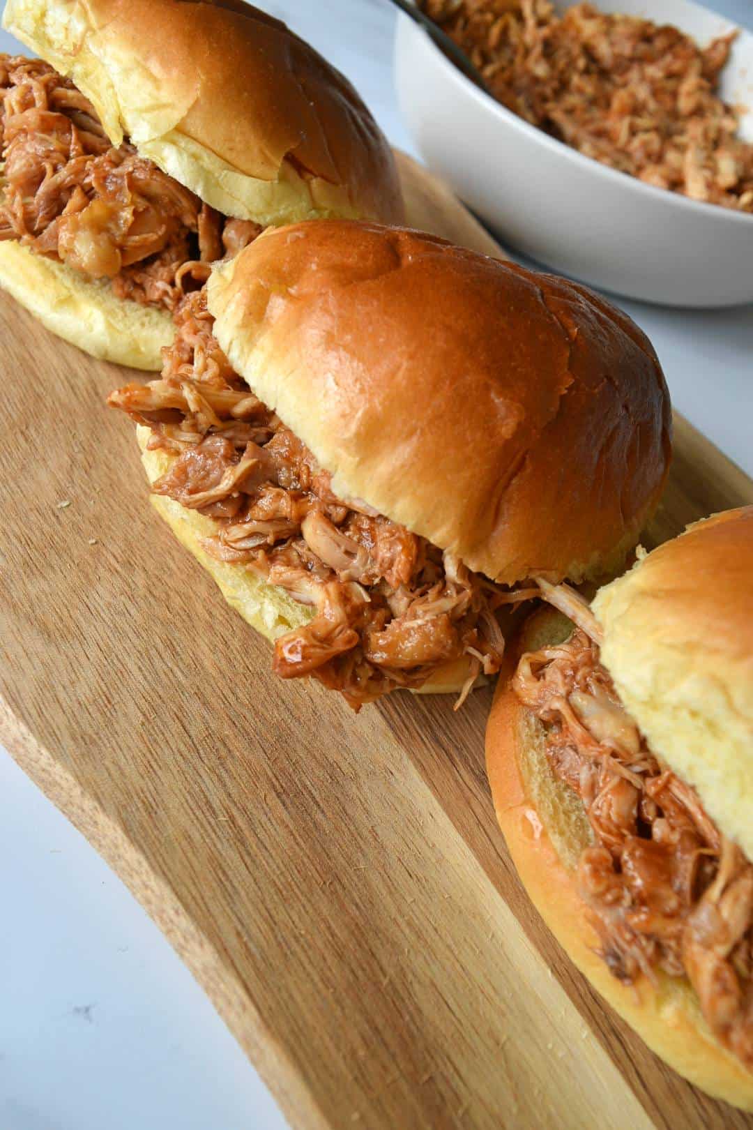 BBQ chicken sandwiches on a wooden board.