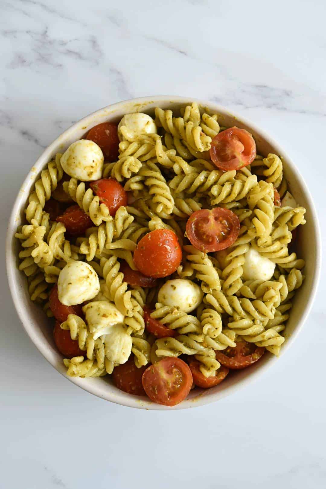 Pasta salad with mozzarella, tomatoes and pesto.