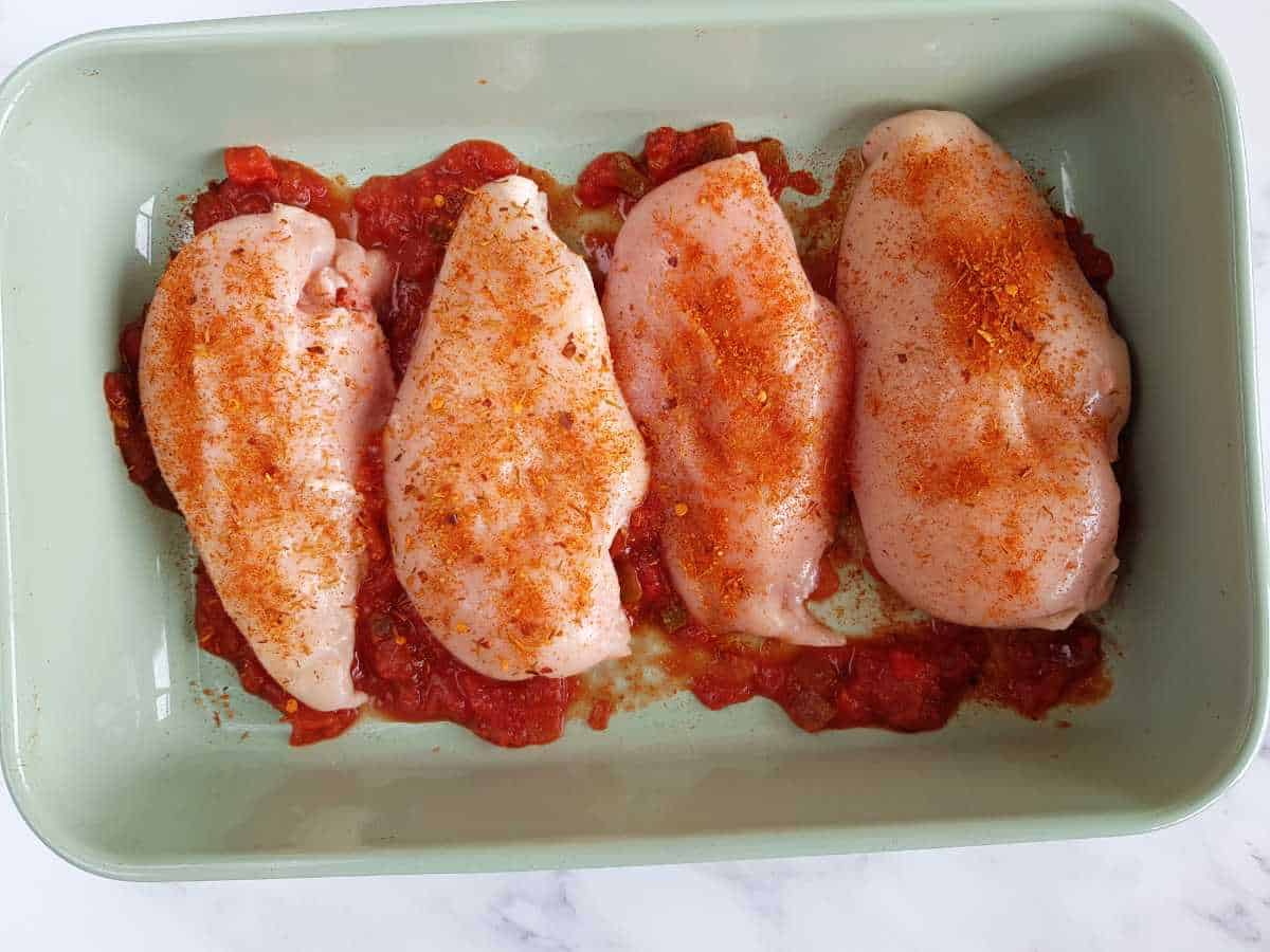 Chicken breasts with taco seasoning in a casserole dish.