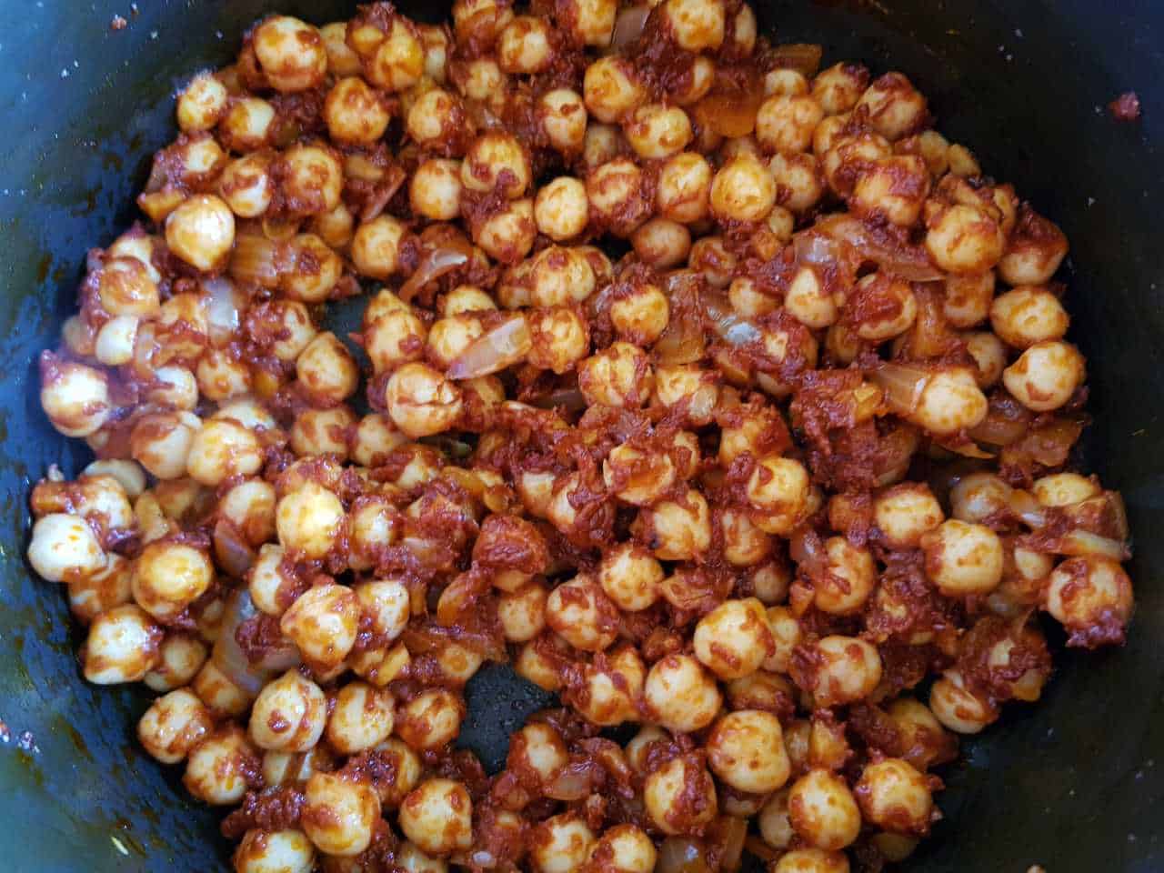 Chickpeas in a pot with tomato paste and spices.