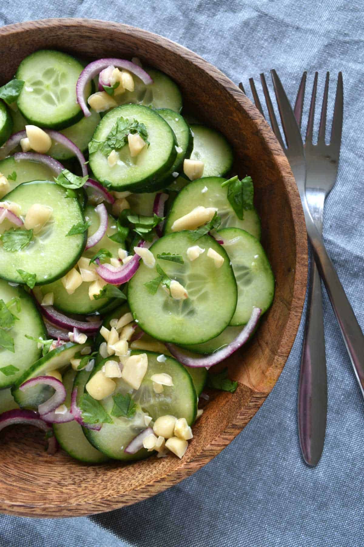 Cucumber salad in a wooden bowl with two forks on the side.