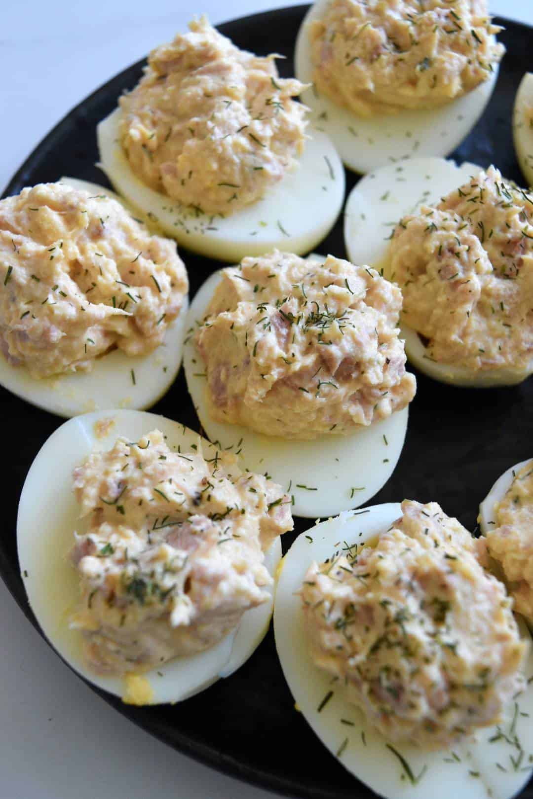 Tuna deviled eggs on a black plate.