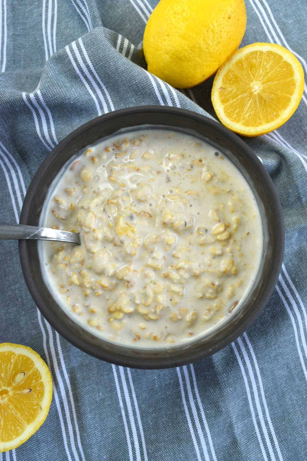 Lemon curd overnight oats in a bowl with a spoon. Lemons on the side.