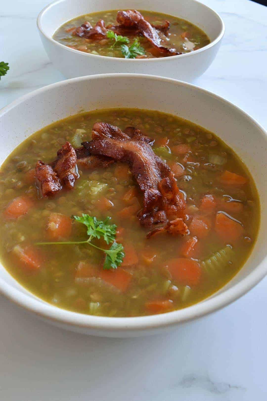 Lentil and bacon soup in a bowl topped with crispy bacon.