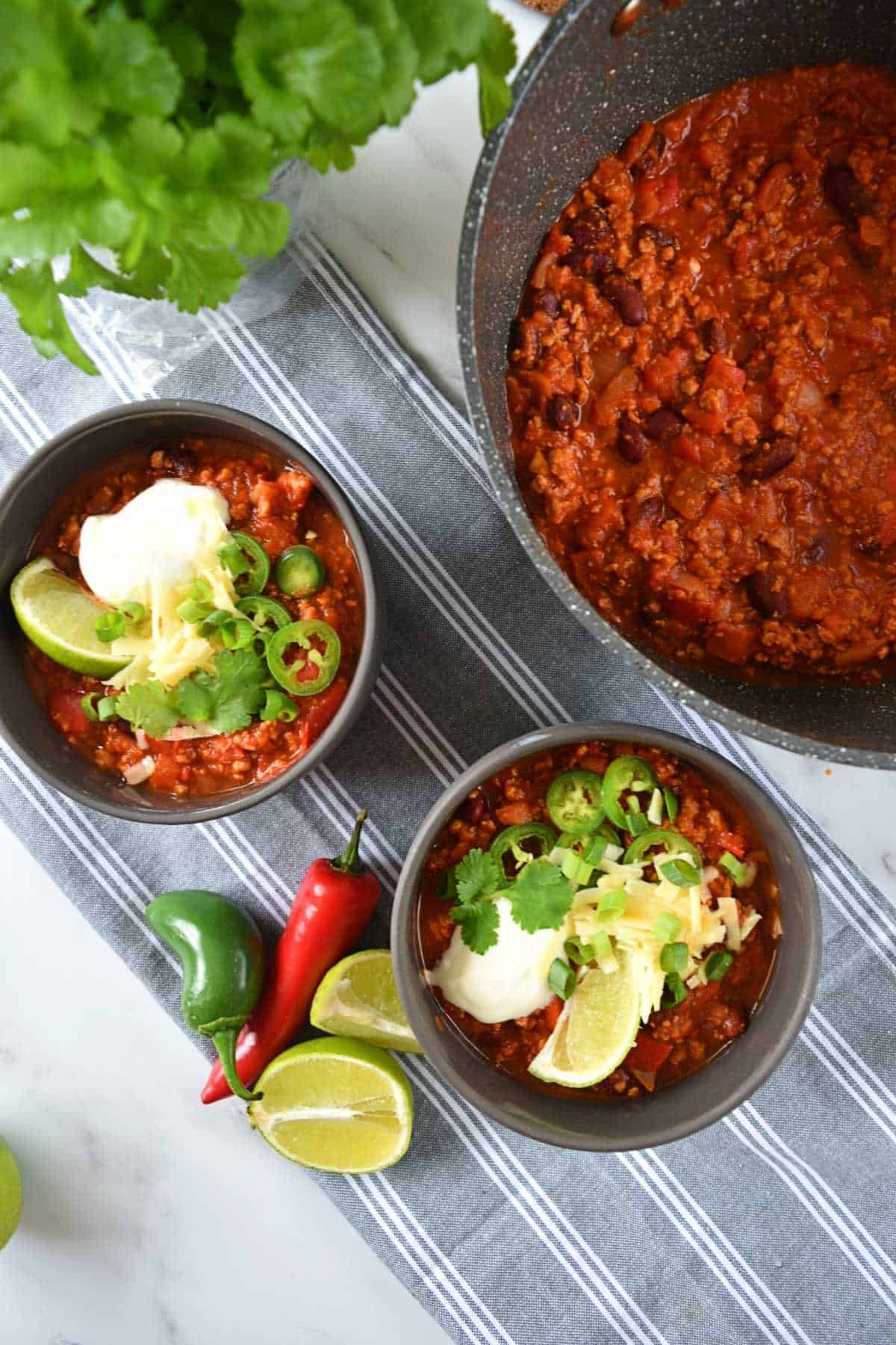One pot turkey chili in a pot with two bowls served on the side.