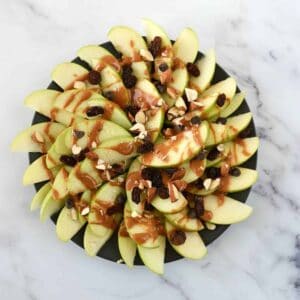 Peanut butter apple nachos on a plate on a marble table.