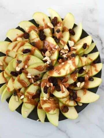 Peanut butter apple nachos on a plate on a marble table.