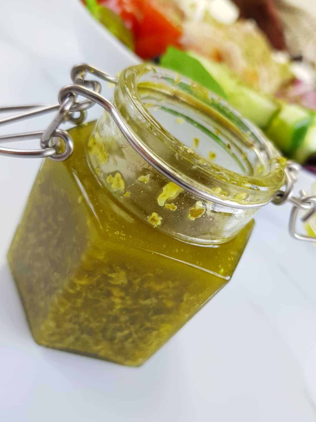 Pesto vinaigrette in a jar with salad in the background.