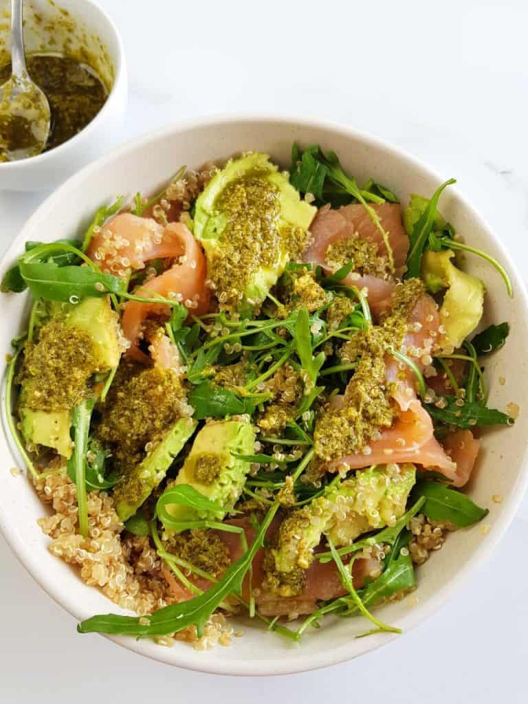 Smoked salmon and quinoa salad with avocado and arugula in a bowl.