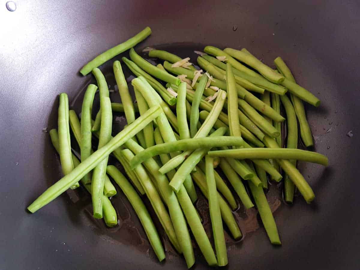 Green beans cooking in a wok.