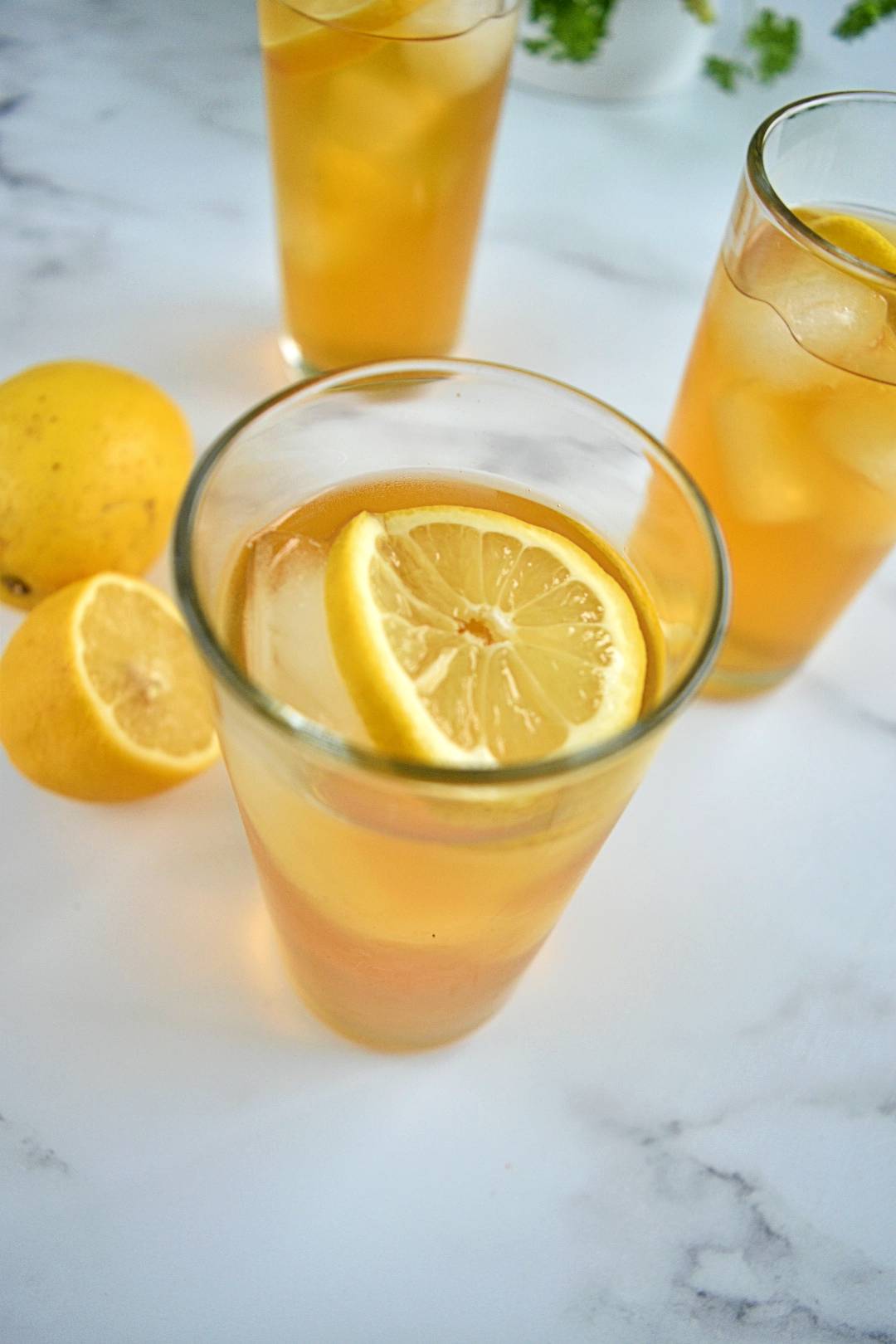 Rooibos iced tea in glasses with ice cubes and lemon slices.