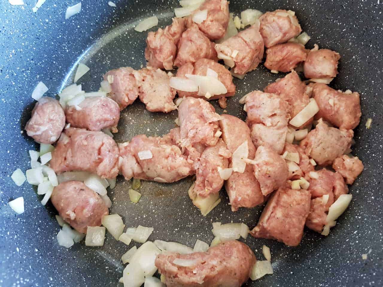 Sausages and onion in a pot.