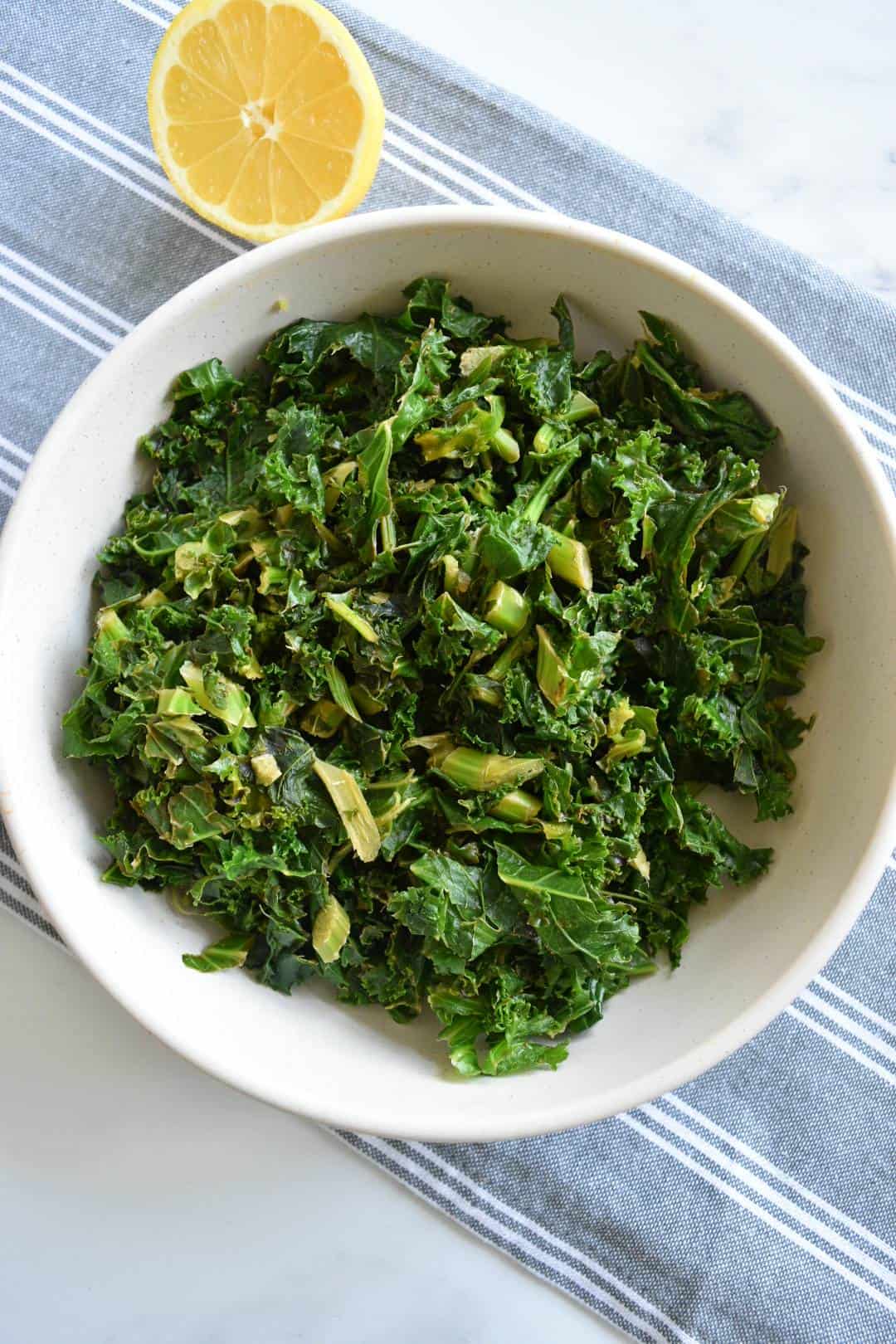 Stewed kale in a bowl with a lemon on the side.
