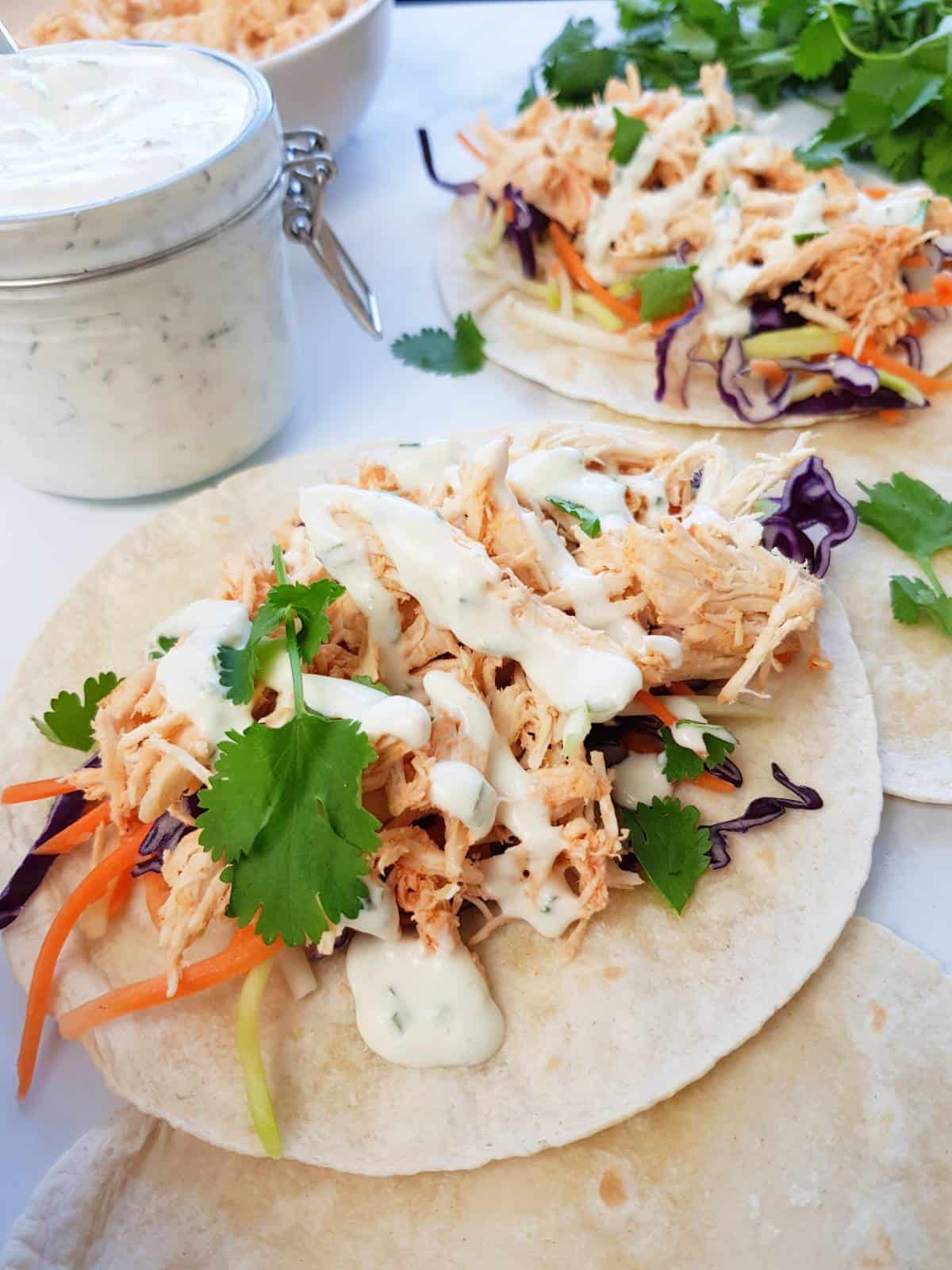 Buffalo chicken tacos with cilantro and ranch on the side.