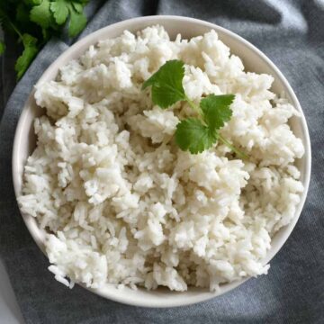 Jasine rice with coconut milk in a bowl, garnished with fresh cilantro.