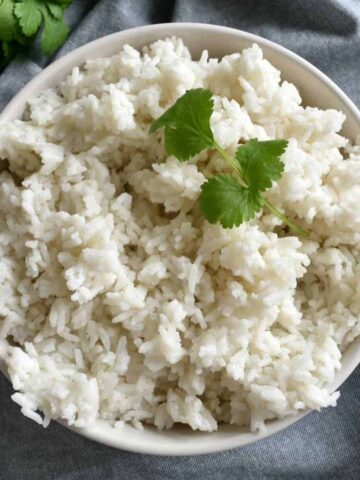 Jasine rice with coconut milk in a bowl, garnished with fresh cilantro.