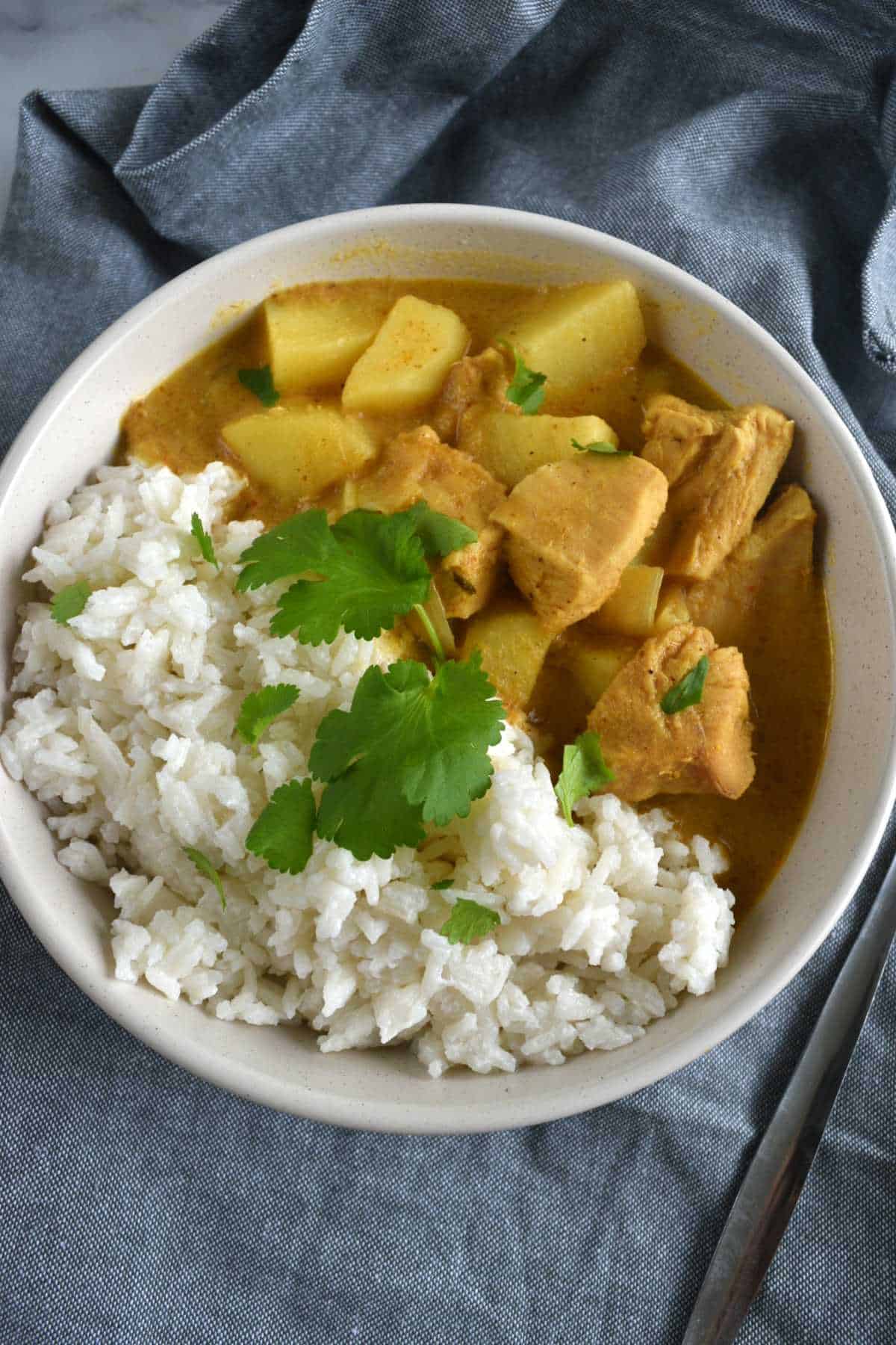 Chicken curry in a bowl with rice and cilantro.