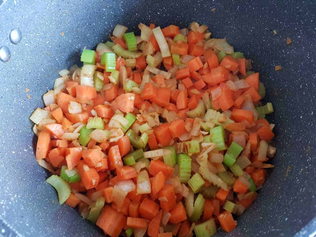 Carrots, celery, onion cooking in a pot.