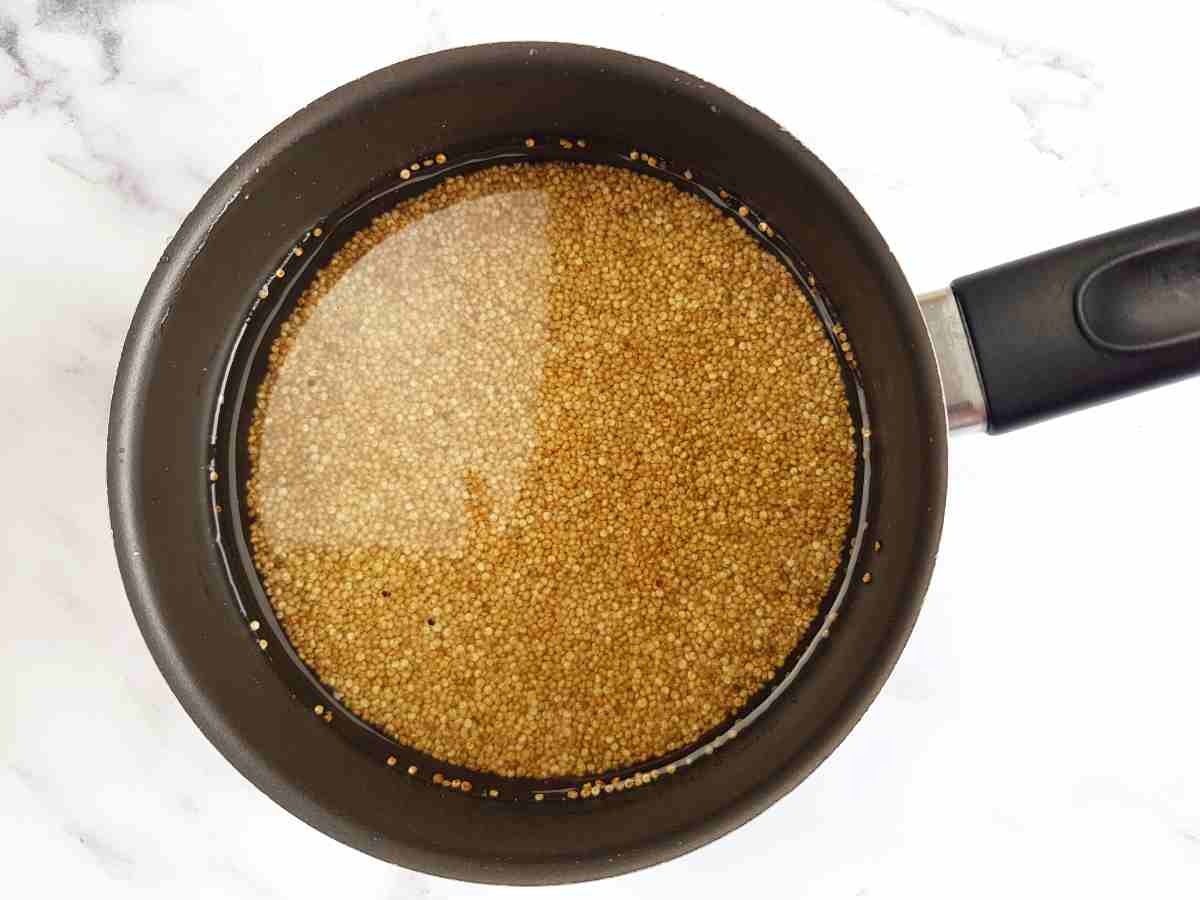 Quinoa in a black saucepan on a marble table.