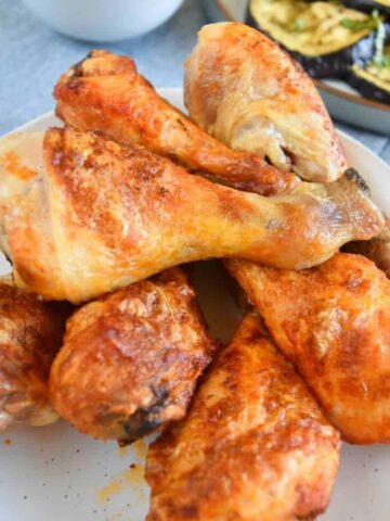 Air fried buffalo chicken legs stacked on a plate.