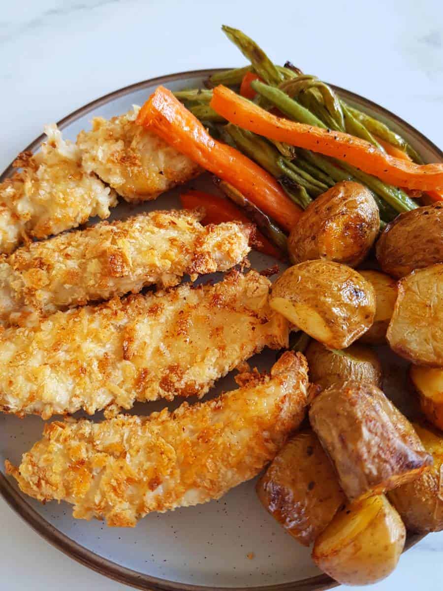 Breaded chicken on a plate with roasted vegetables.