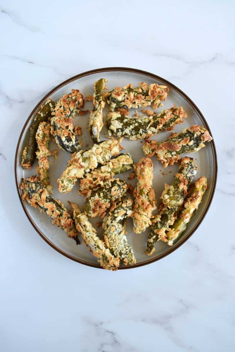 Air fried pickles on a plate on a marble table.