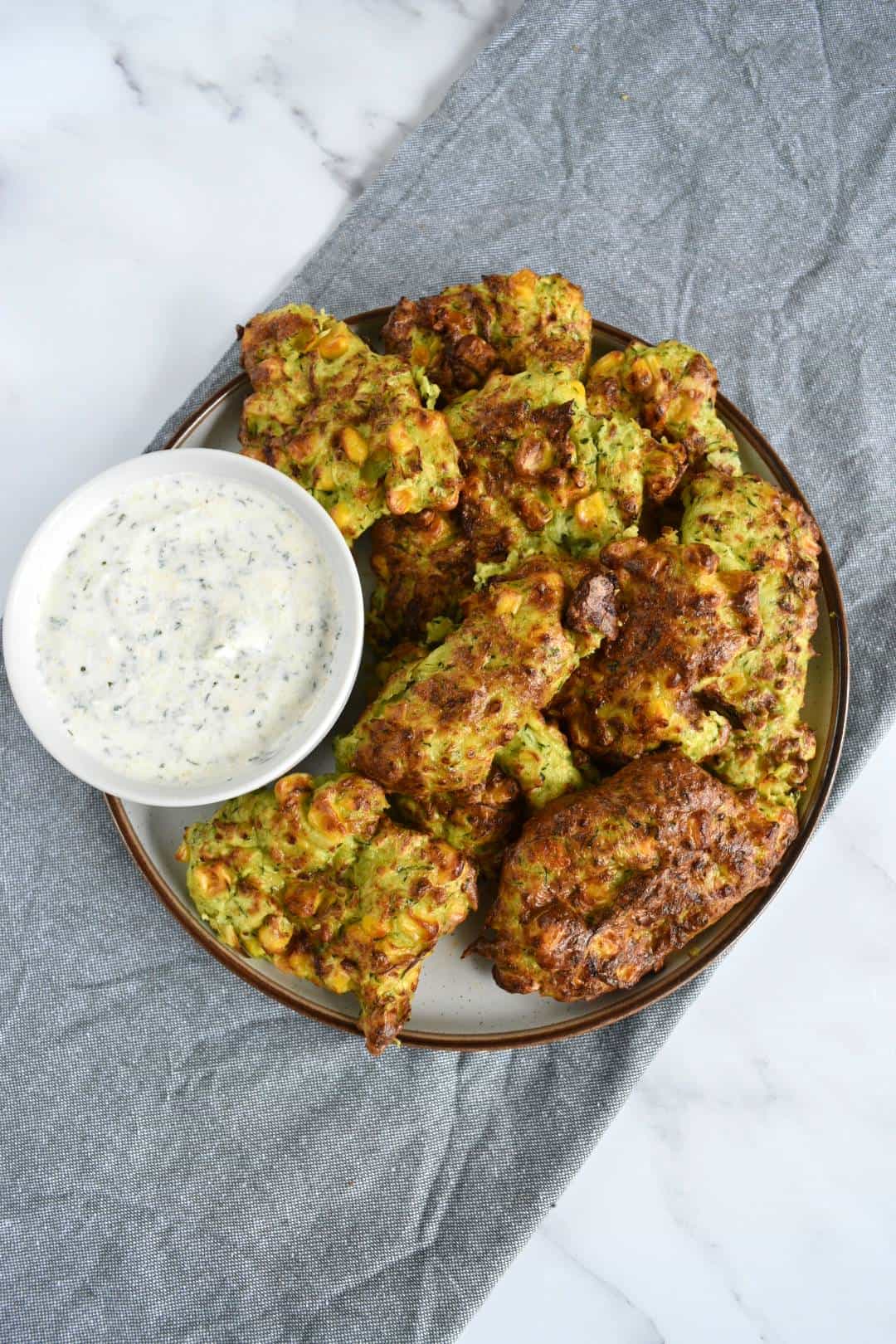 Air fryer zucchini fritters with yogurt dip on the side.