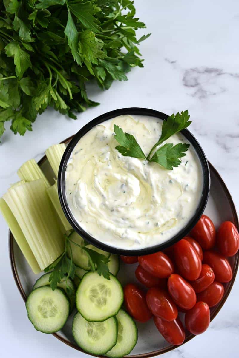 Authentic Tzatziki sauce on a plate with veggies on the side.