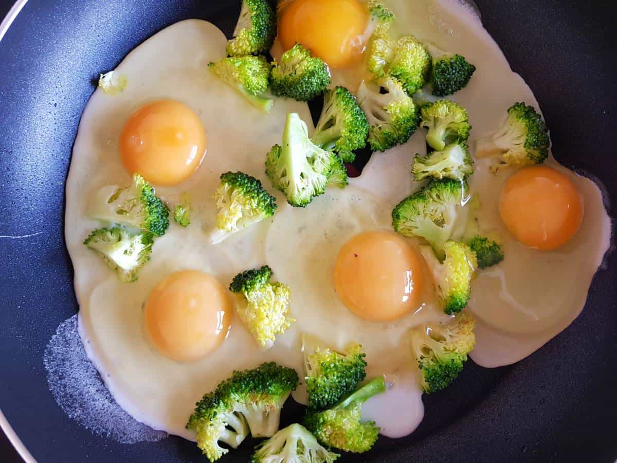 Broccoli and eggs in a frying pan.