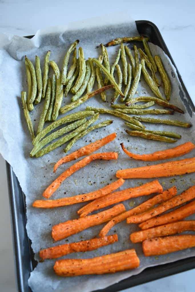 Roasted carrots and green beans on a baking tray.