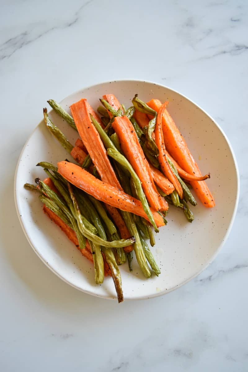 Roasted carrots and green beans on a plate.