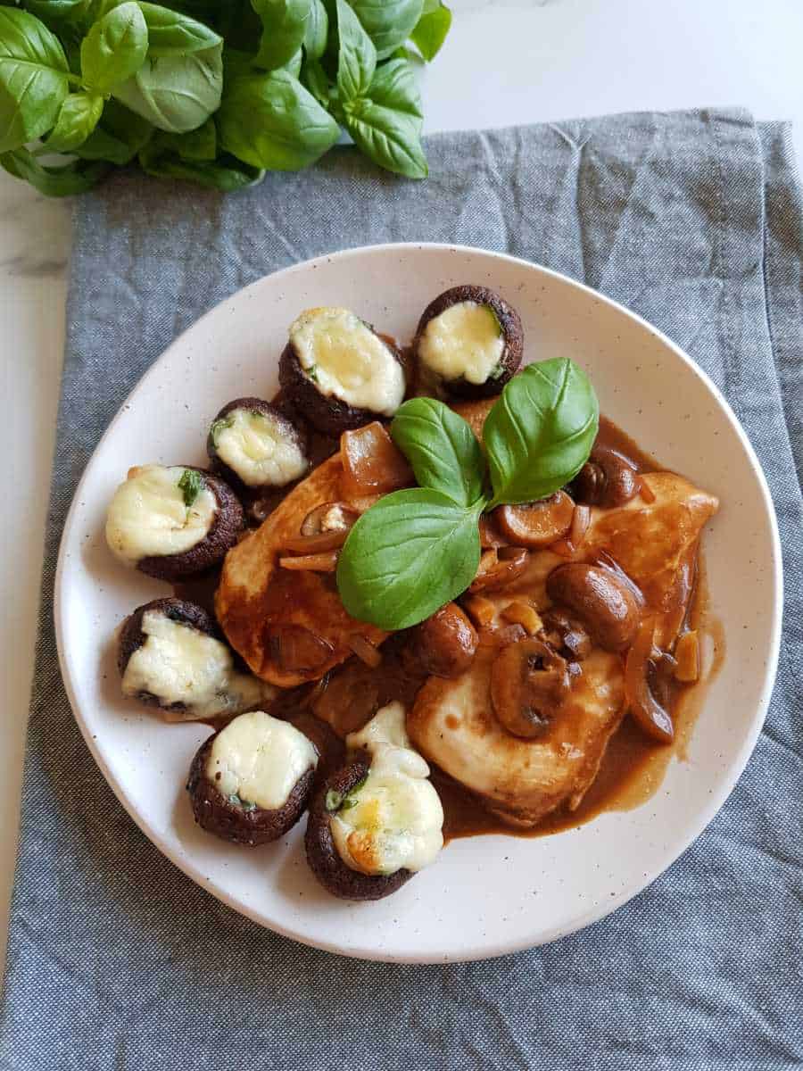 Chicken marsala on a plate with mushrooms and basil.