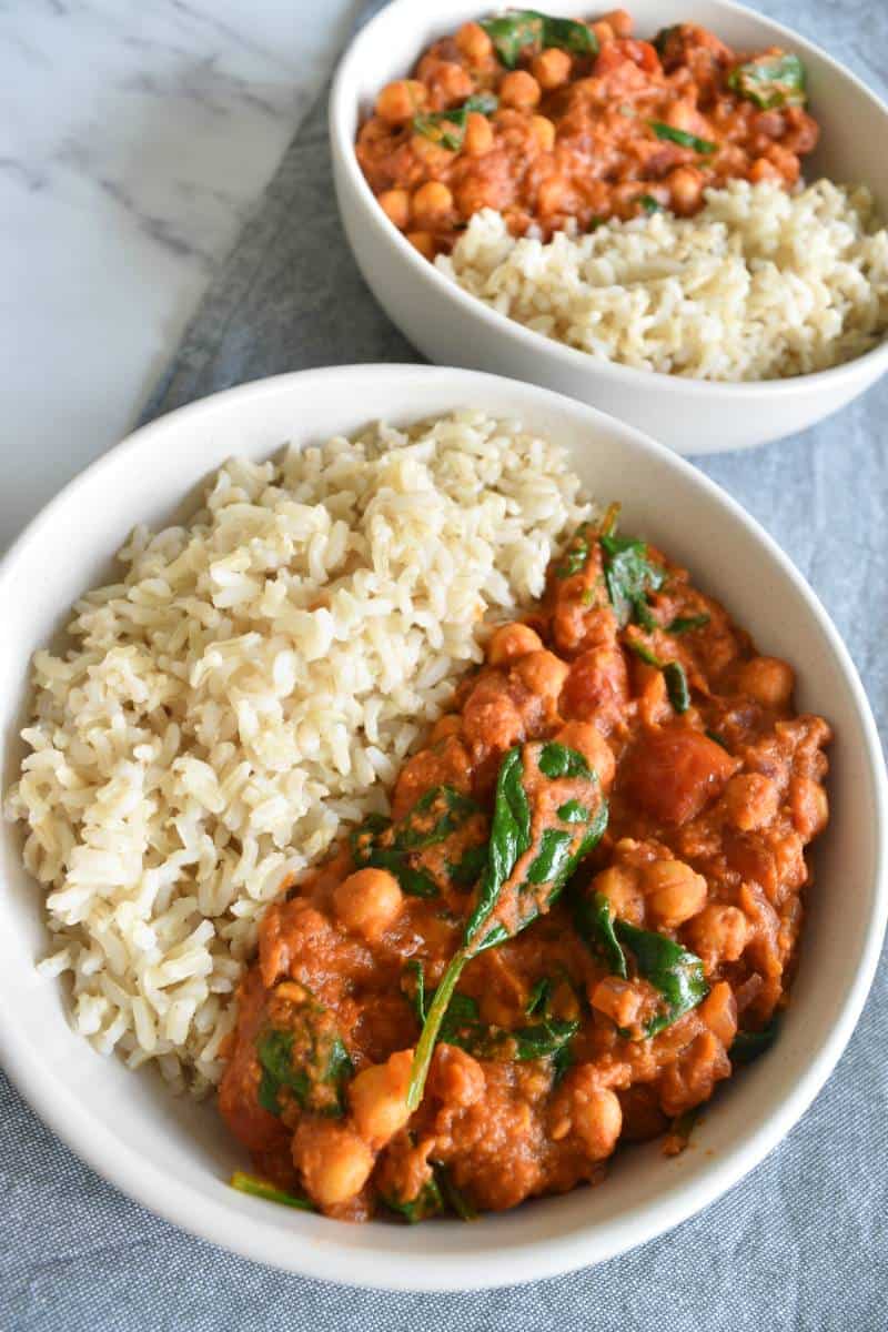 Chickpea and hummus curry in white bowls on a marble table.