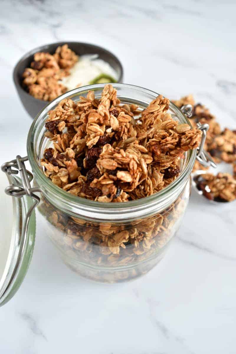 Cinnamon raisin granola in a jar on a marble table.