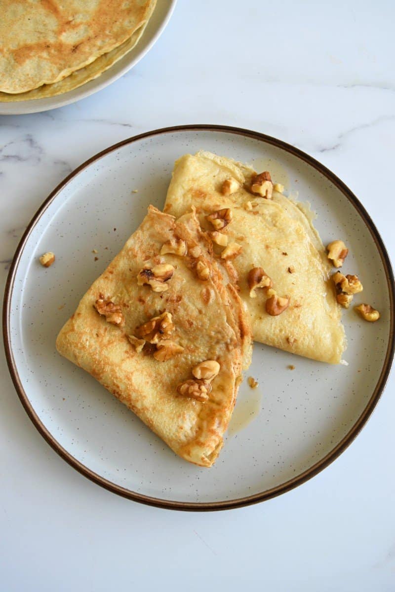 Crepes with maple syrup and walnuts on a plate.