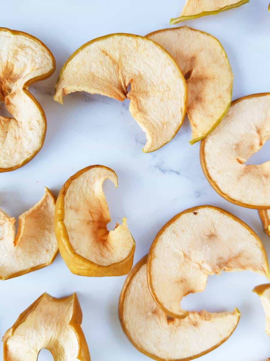 Dried apple slices on a marble table.